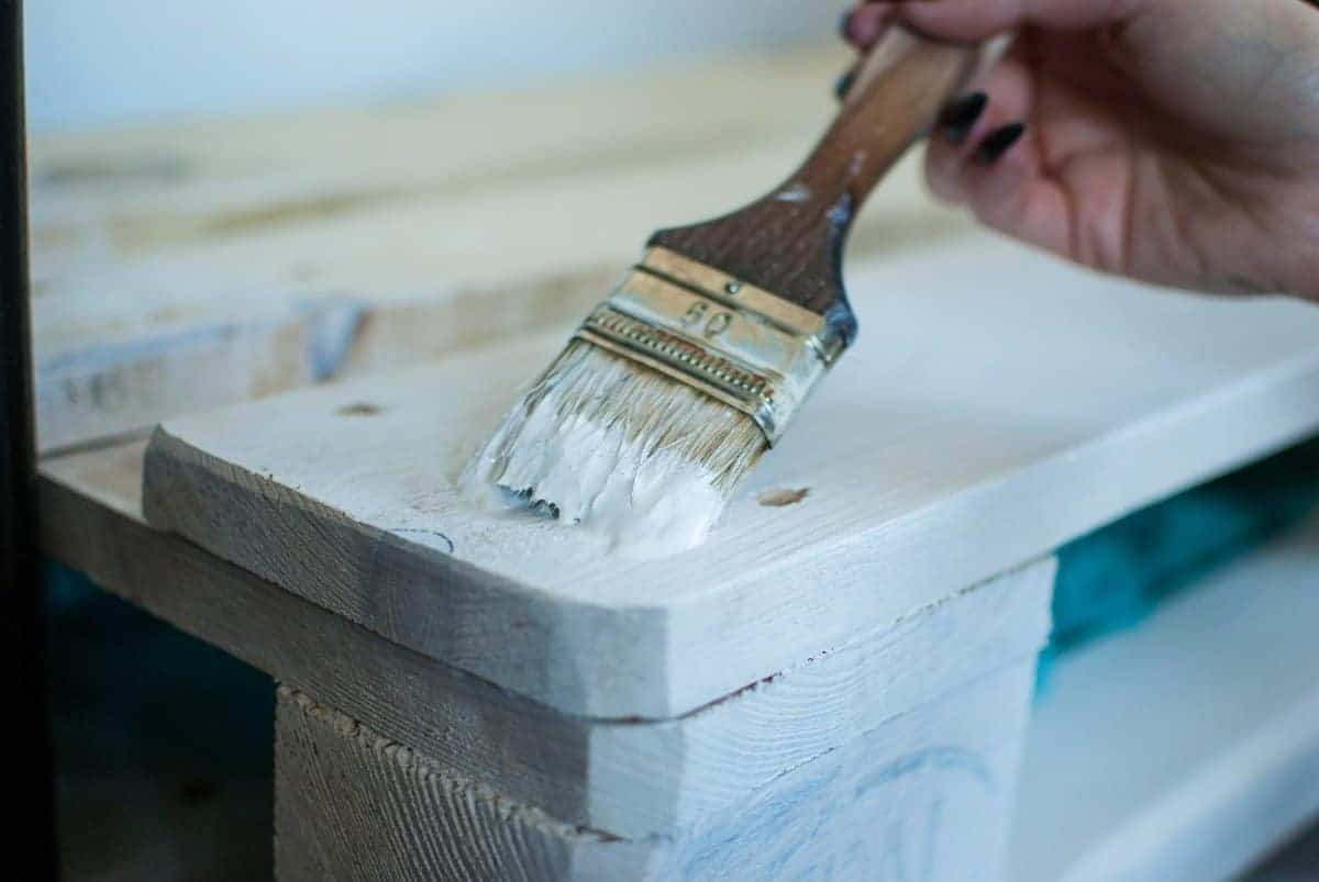 painting wooden plank white with a paintbrush