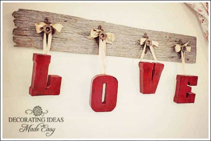 wooden plank with letters hanging from knobs forming word love