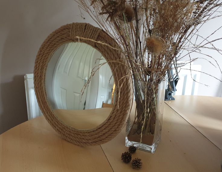 diy rope mirror frame next to a vase with dry grass