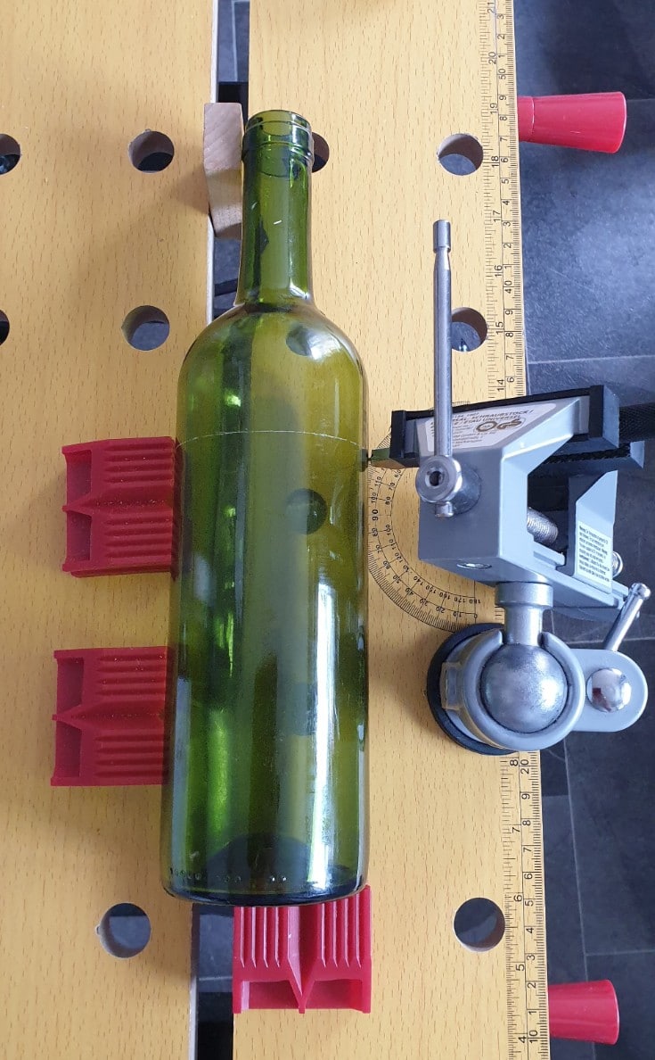 image shows how to cut glass bottles using a glass cutter in a vice